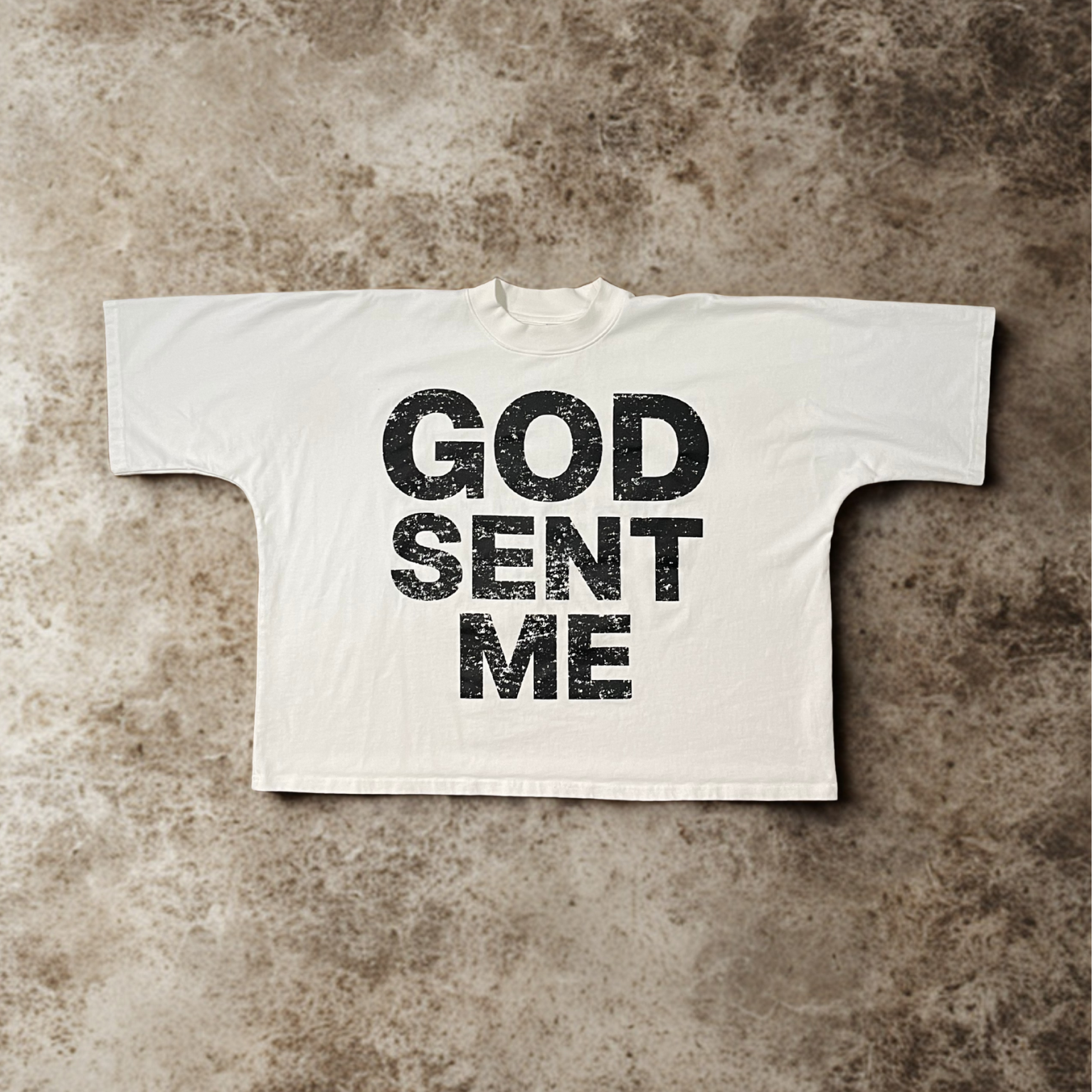 White t-shirt with 'GOD SENT ME' text on a textured brown background